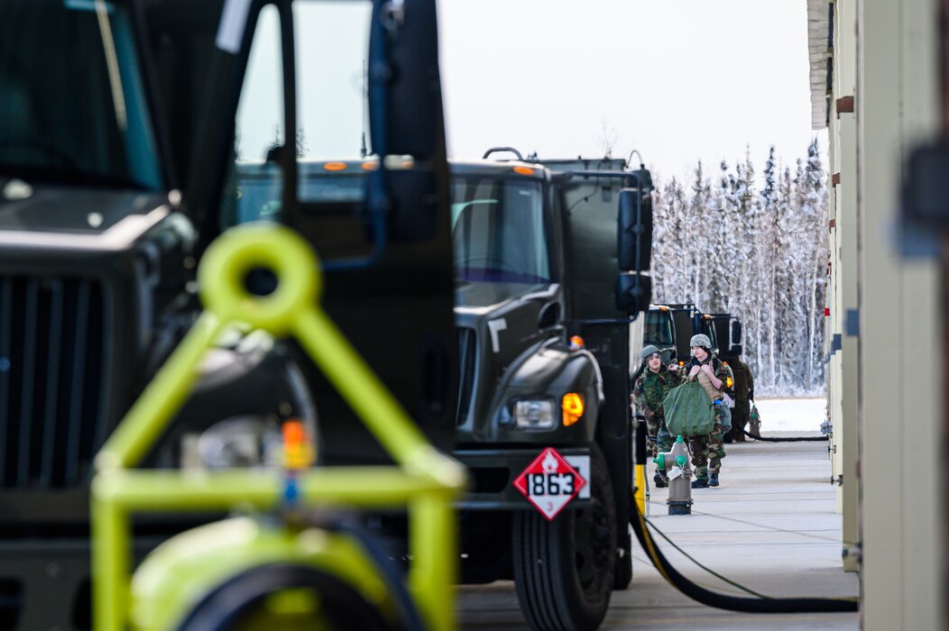 U.S. Airmen assigned to the 355th Aircraft Maintenance Unit walk on the flightline in Mission Oriented Protective Posture gear during a mini generation on Eielson Air Force Base, Alaska, Oct. 26, 2022.