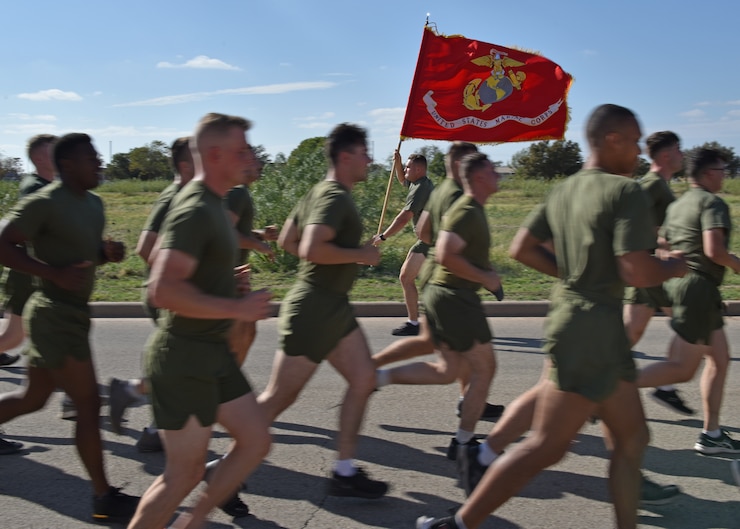 A Marine carries the guidon during a moto-run at Goodfellow Air Force Base, Texas, Nov. 3, 2022. The marines passed the guidon to each other to run around the formation. (U.S. Air Force photo by Airman 1st Class Zachary Heimbuch)