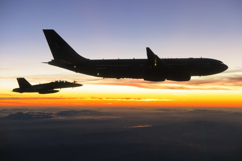 Large and smaller aircraft fly together at twilight.
