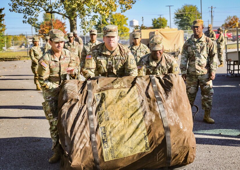 Soldiers work as a team opening a tent.