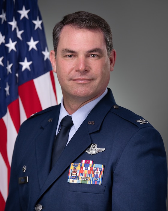Col Scott Meyer in front of a grey background with an American flag.