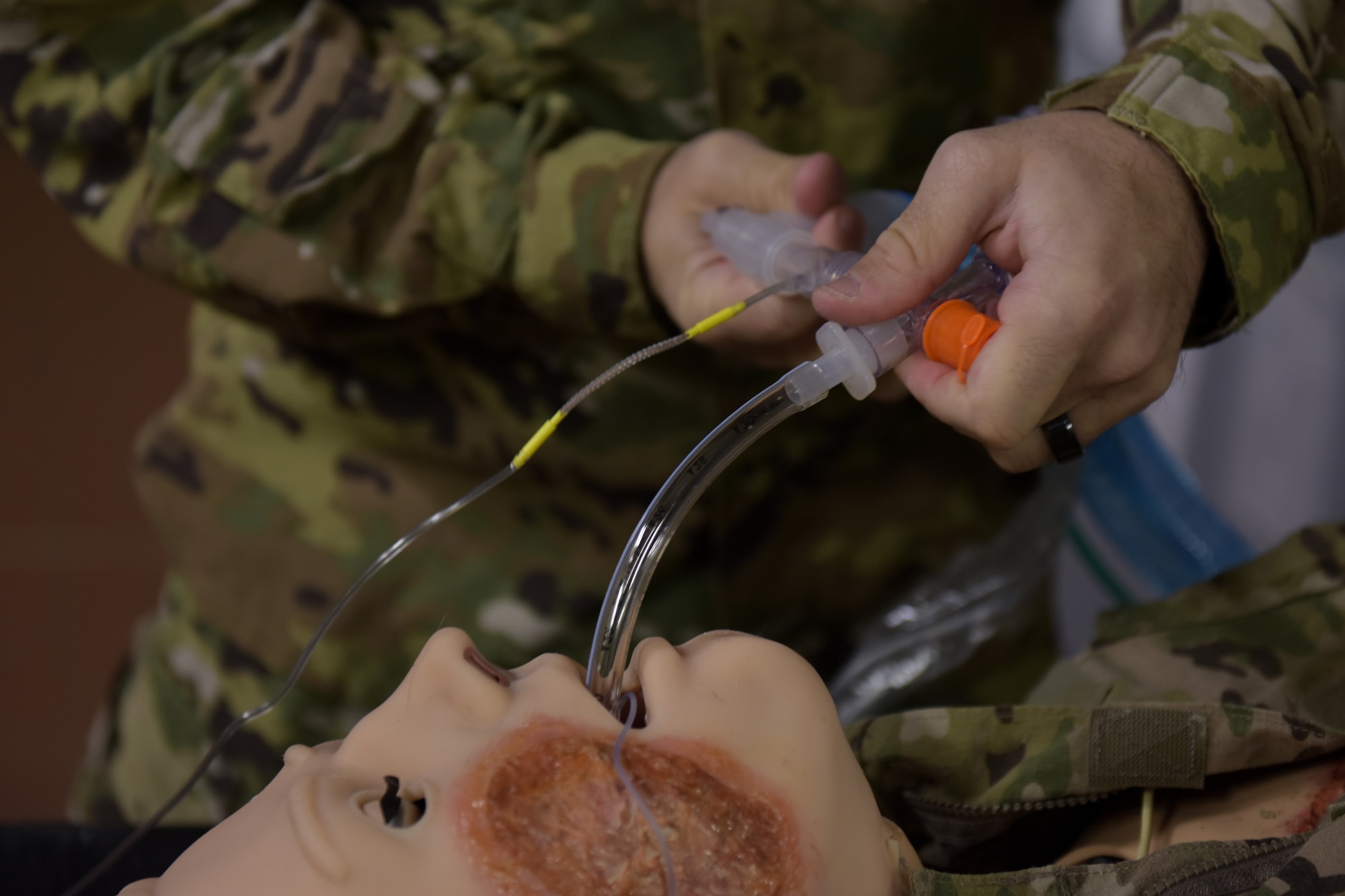 A man puts a tube down a mannequins throat as part of an exercise.