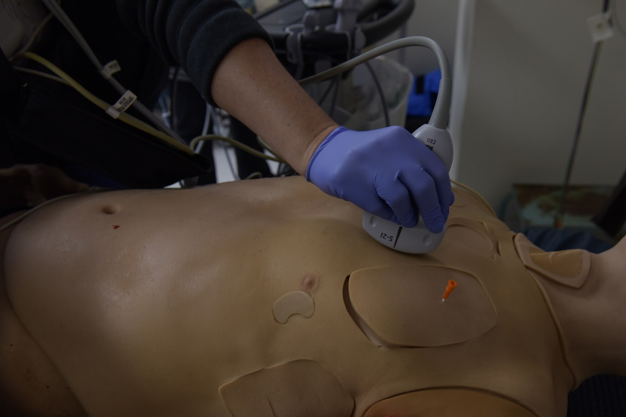 A woman uses an ultrasound machine on a mannequin