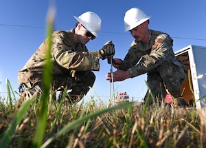 U.S. Air Force Staff Sgt. Jared Clark, 509th Civil Engineering Squadron Electrical Systems Craftsman and Airman 1st Class Gordon Stenersen, 509th Civil Engineering Squadron Electrical Systems Craftsman, drive stakes to hold the winged-out threshold bar in place at Whiteman Air Force Base, Missouri, September 26, 2022.