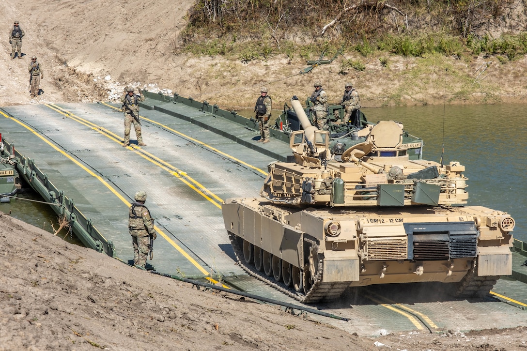 A tank prepares to cross a bridge over a small river.