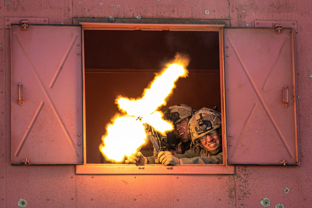 Two soldiers fire a weapon from the window of a bin.