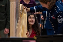 U.S. Air Force Master Sgt. Gréta K Ásgeirsson shows audience members how to play the harp during intermission at The United States Air Force Band’s Fall Tour concert at Battle Ground High School, Battle Ground, Wash., Oct. 24, 2022. Audience members were able to speak with members of The Band one-on-one, test instruments and learn more about The Band’s mission during intermission and before and after each concert. (U.S. Air Force photo by Kristen Wong)
