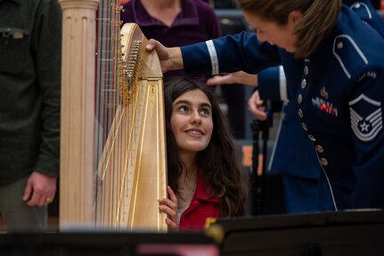 U.S. Air Force Master Sgt. Gréta K Ásgeirsson shows audience members how to play the harp during intermission at The United States Air Force Band’s Fall Tour concert at Battle Ground High School, Battle Ground, Wash., Oct. 24, 2022. Audience members were able to speak with members of The Band one-on-one, test instruments and learn more about The Band’s mission during intermission and before and after each concert. (U.S. Air Force photo by Kristen Wong)