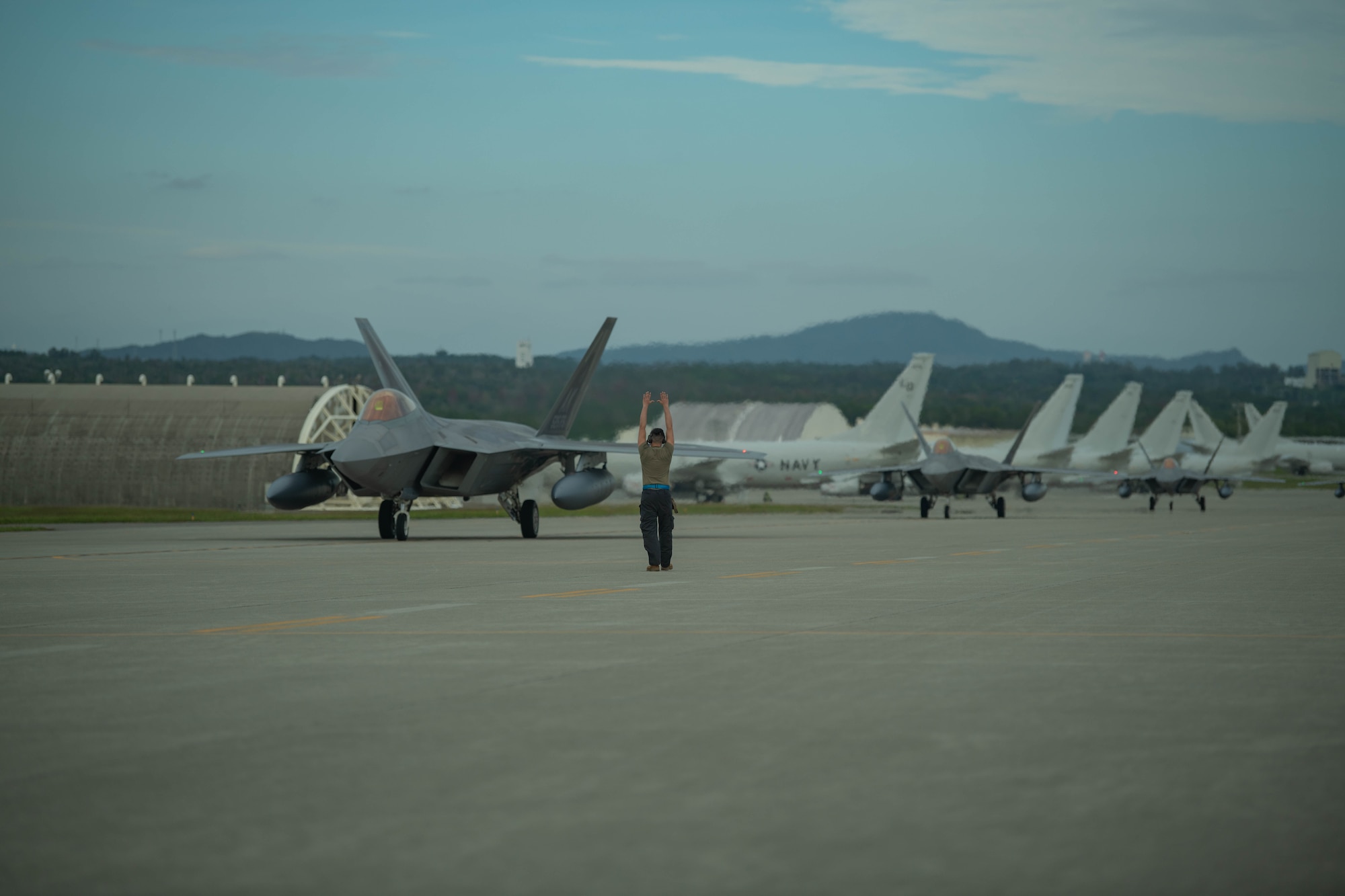 Maintainer directs line of F-22 Raptors.