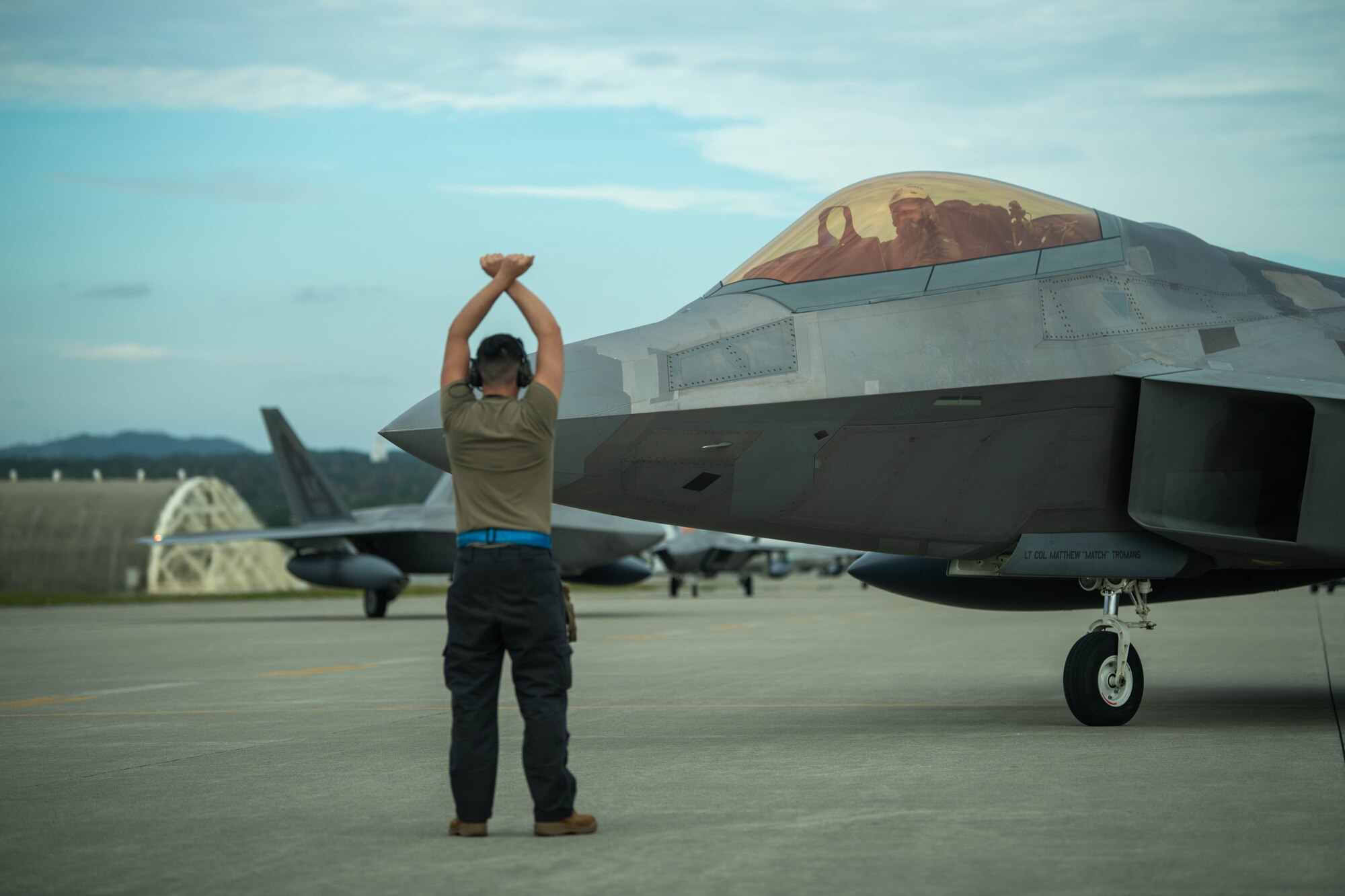 Maintainer directs F-22 Raptor.