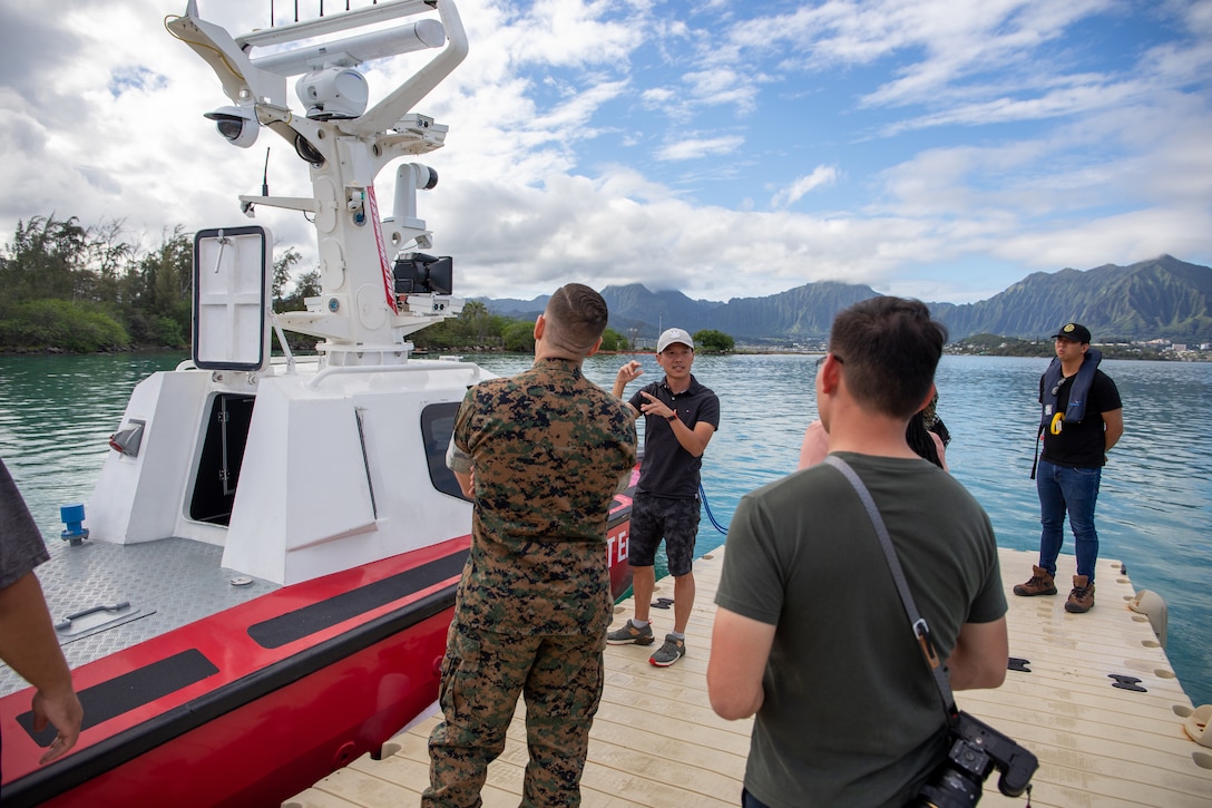 NG Chee Wee, center, ST Engineering, delivers a demonstration brief to distinguished visitors during a capabilities demonstration of an Unmanned Surface Vessel (USV) featuring the AUTONOMAST system at Marine Corps Base Hawaii (MCBH), Oct. 26, 2022. U.S. Indo-Pacific Command Science and Technology Office hosted the Singapore Ministry of Defense, Future Systems and Technology Directorate sponsored demonstration. The AUTONOMAST system developed by ST Engineering, a global technology, defense and engineering group headquartered in Singapore, is designed to convert any manned vessel into a USV, with all-round situational awareness capabilities for tracking stationary or moving surface obstacles for safe autonomous navigation. The demonstration, with support from MCBH Waterfront Operations, focused on autonomous navigation in congested waters and force protection maneuvers. (U.S. Marine Corps photo by Lance Cpl. Terry Stennett)