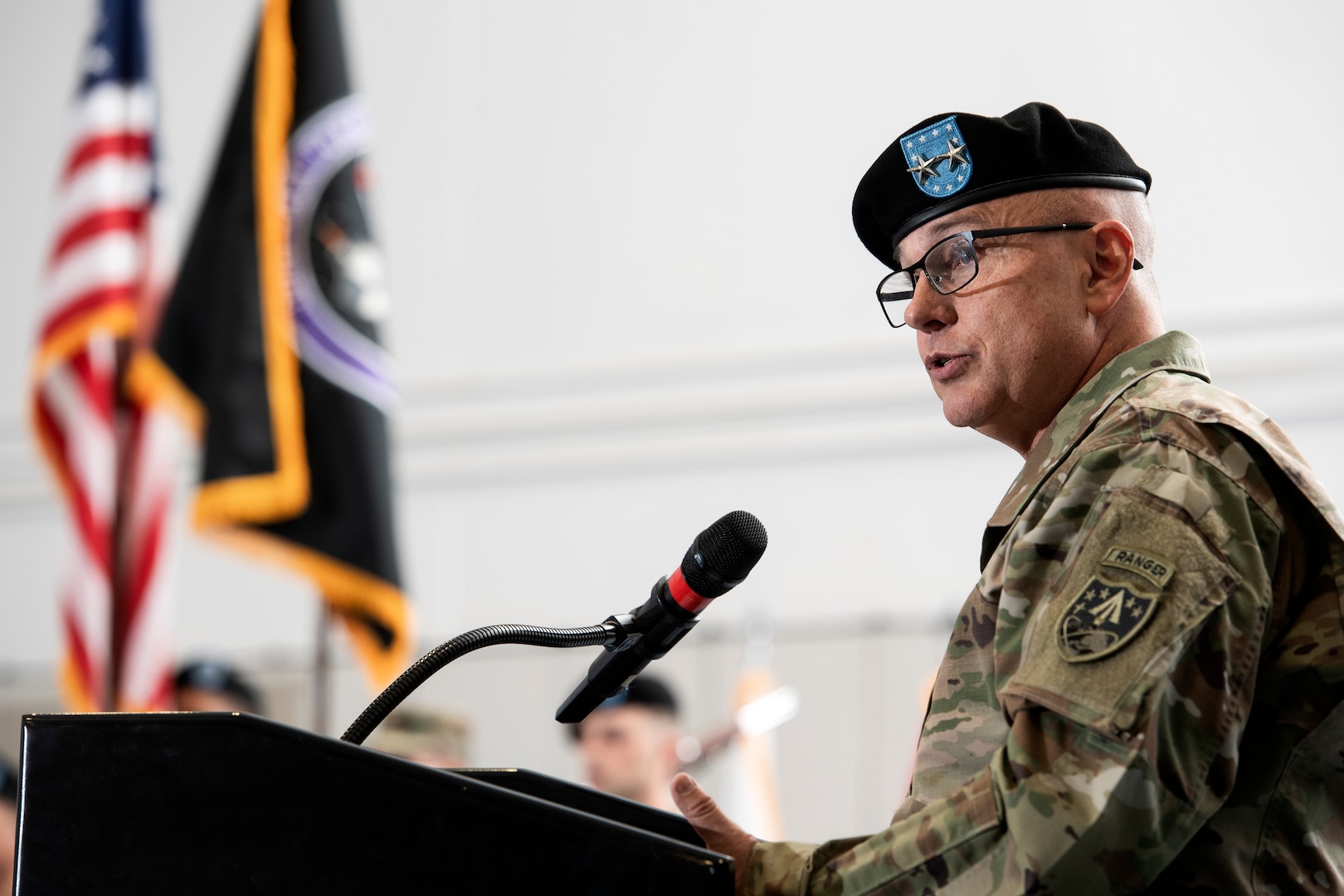 Man in military uniform and beret speaks at a podium