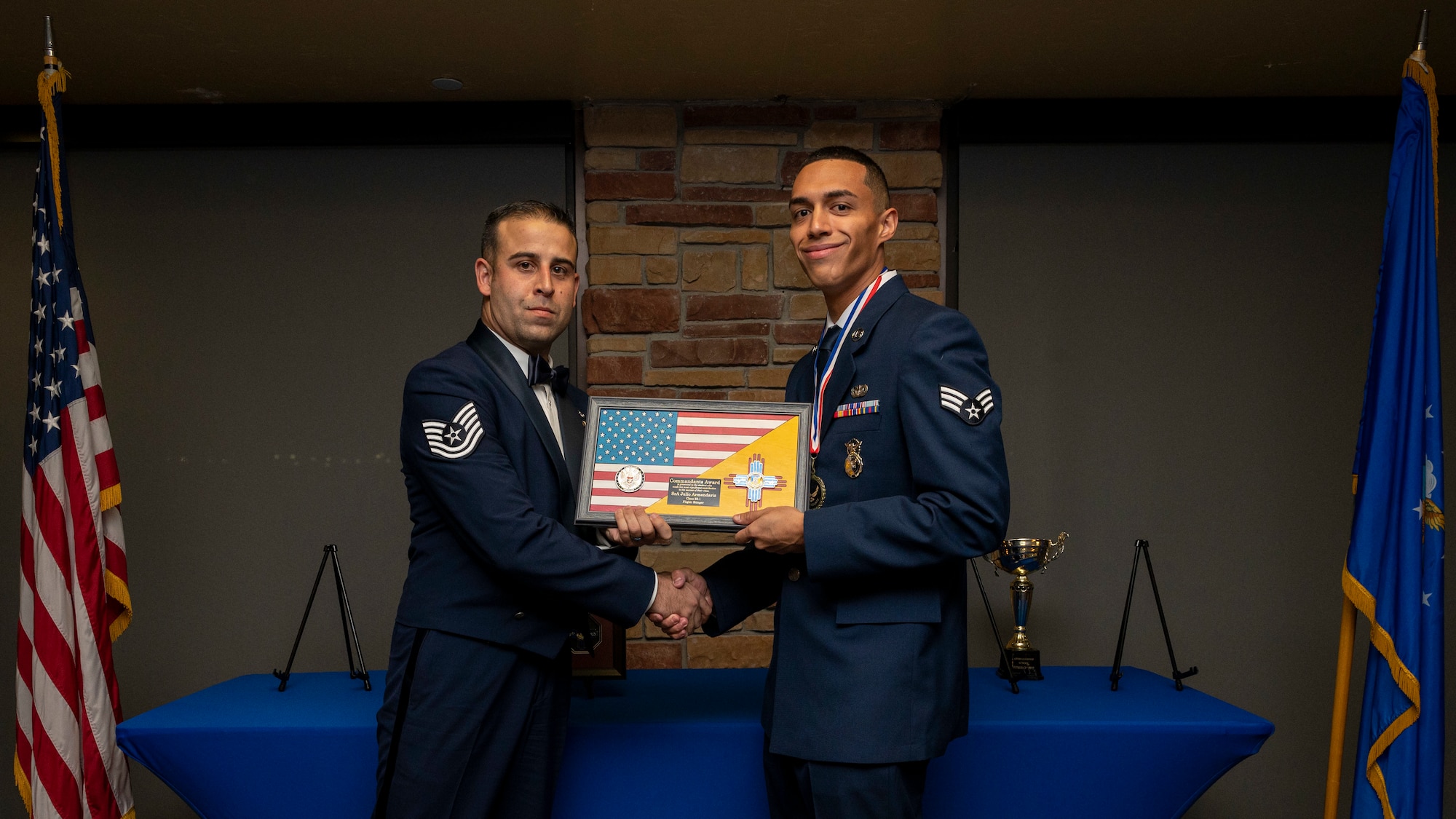 U.S. Air Force Senior Airman Julio Armendariz, right, accepts the Commandant's Award from U.S. Air Force Tech. Sgt. Matthew Cabral, 49th Civil Engineer Squadron, command support staff section chief, during an Airman Leadership School graduation at Holloman Air Force Base, New Mexico, Nov. 3, 2022.