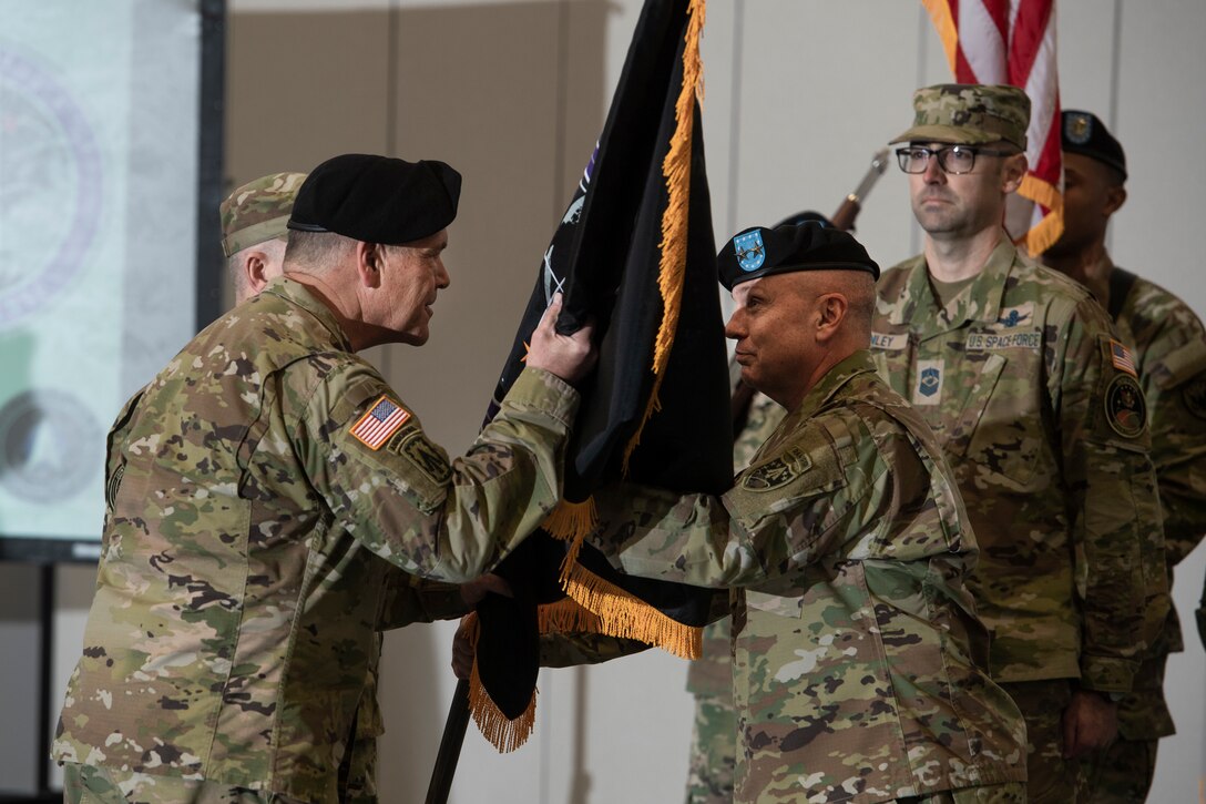 Man in uniform accepts flag from man in military uniform