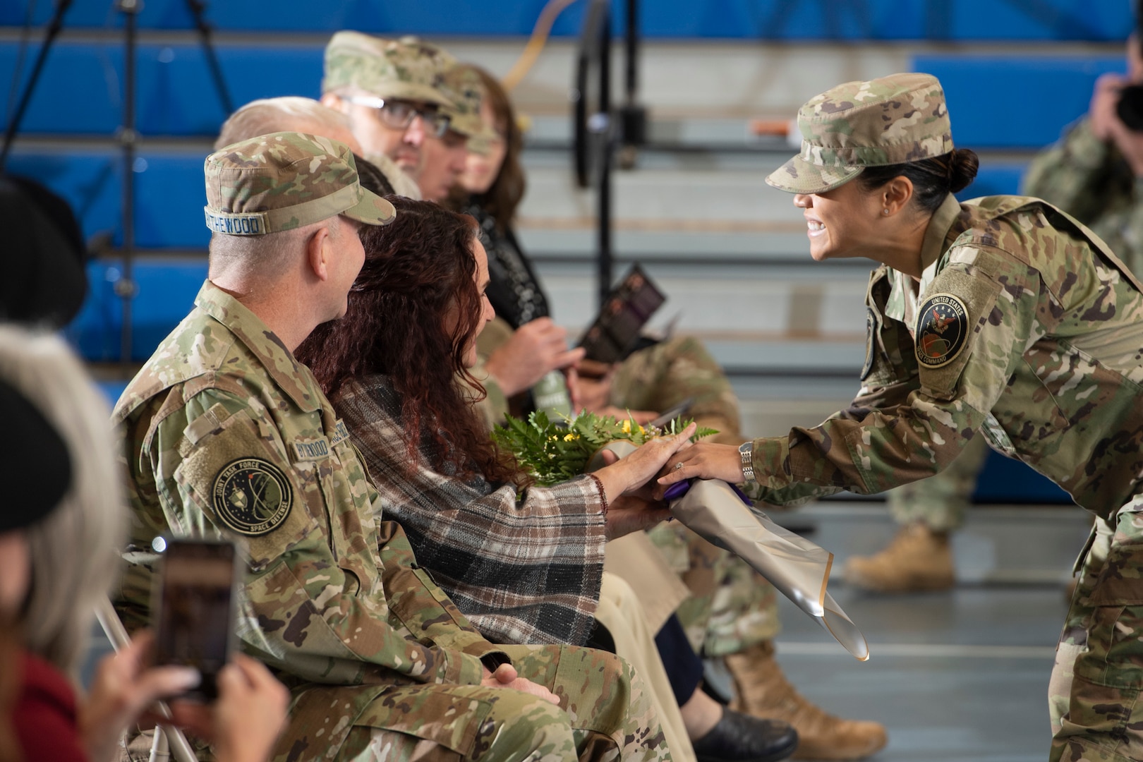 Woman in military uniform hands bouquet of roses to a woman