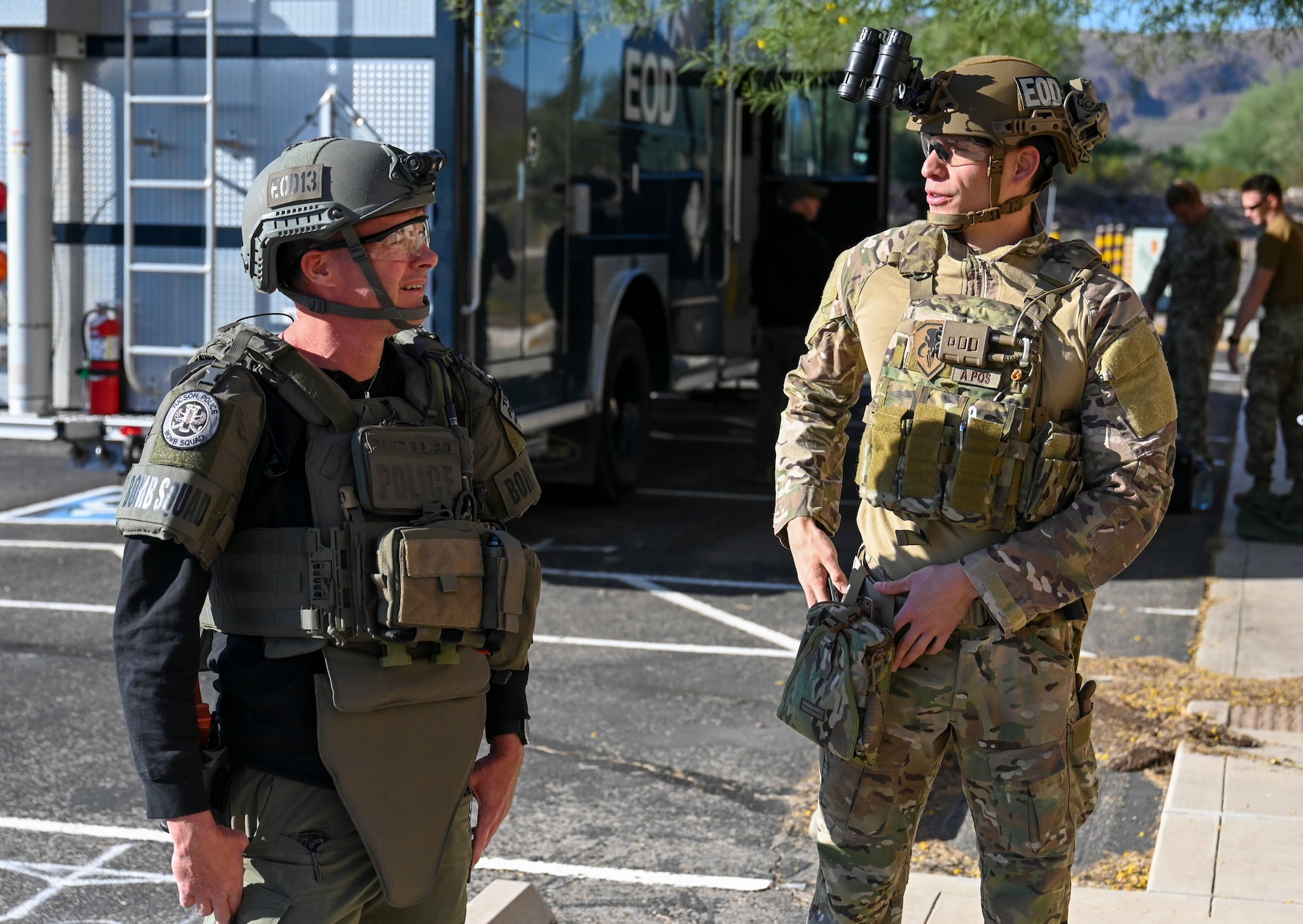A Tucson police officer and Air Force Airmen stand next to each other wearing protective helmets and vests