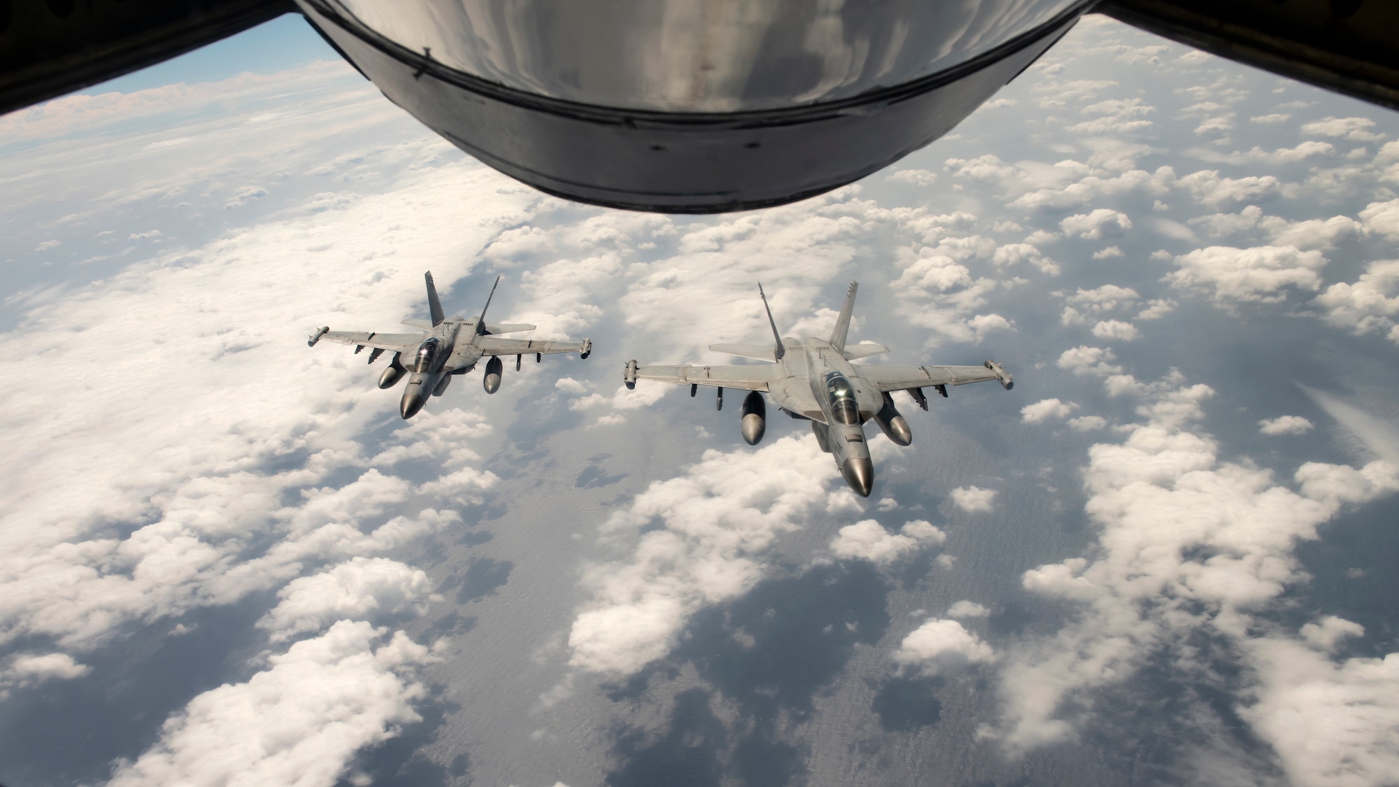 U.S. Navy F/A-18 Super Hornets fly behind a  KC-135 Stratotanker assigned to the 909th Air Refueling Squadron after receiving fuel during a joint training exercise over the Pacific Ocean, Oct. 24, 2022. Joint training strengthens partnerships and enhances capabilities, allowing the U.S. to maintain air supremacy and ensure a free and open Indo-Pacific. (U.S. Air Force photo by Senior Airman Jessi Roth)