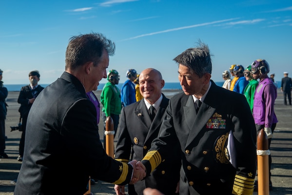 SAGAMI WAN (Nov. 6, 2022) Adm. Sakai Ryo, right, Japan Maritime Self-Defense Force (JMSDF) chief of staff, and Adm. Mike Gilday, center, chief of naval operations, greet Rear Adm. Buzz Donnelly, commander, Task Force 70, on the flight deck of the U.S. Navy’s only forward-deployed aircraft carrier, USS Ronald Reagan (CVN 76), prior to a ship tour as part of the JMSDF Fleet Review 2022 in the Sagami Wan, Nov. 6. Ronald Reagan, the flagship of Carrier Strike Group 5, provides a combat-ready force that protects and defends the United States, and supports alliances, partnerships and collective maritime interests in the Indo-Pacific region. (U.S. Navy photo by Mass Communication Specialist 3rd Class Gray Gibson)