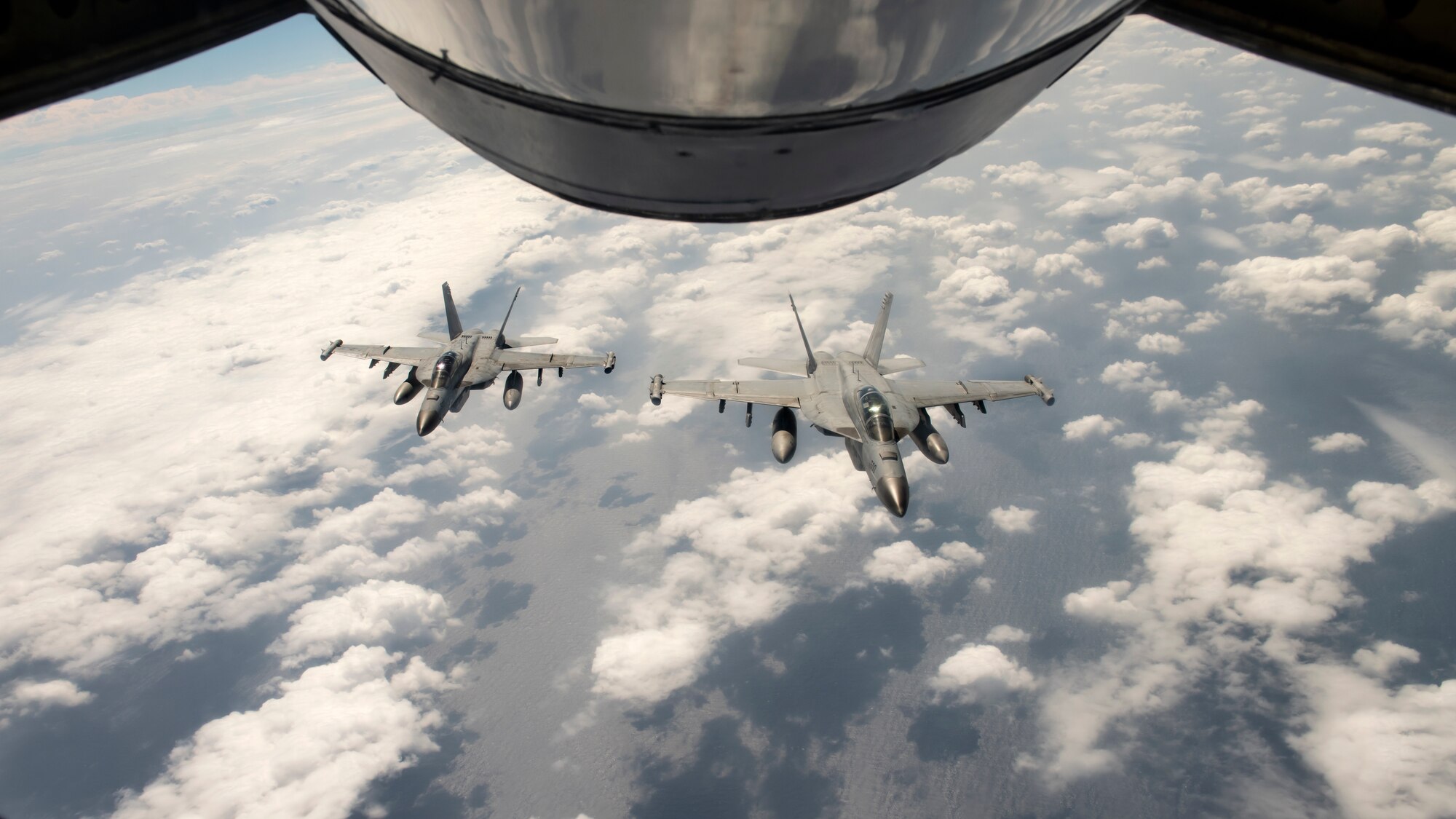 U.S. Navy F/A-18 Super Hornets fly behind a  KC-135 Stratotanker assigned to the 909th Air Refueling Squadron after receiving fuel during a joint training exercise over the Pacific Ocean, Oct. 24, 2022. Joint training strengthens partnerships and enhances capabilities, allowing the U.S. to maintain air supremacy and ensure a free and open Indo-Pacific. (U.S. Air Force photo by Senior Airman Jessi Roth)