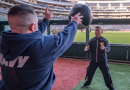 U.S. Navy Lt. Matthew Maccarrone and Builder 1st Class Ryan Tran, both assigned to Public Works Department Navy Yard, throw a medicine ball during a workout hosted by the Washington Nationals baseball team at Nationals Park in Washington, D.C. on Oct. 28, 2022. The workout included multiple stations focused on various muscle groups located throughout the stands, dugouts and field. (U.S. Air Force photo by Jason Treffry)