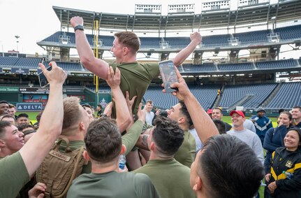 U.S. Marine Corps Lance Corporal Aidan Berne, Guard at Marine Barracks Washington, is lifted in celebration after winning a push-up competition hosted by the Washington Nationals baseball team on Oct. 28, 2022, at Nationals Park in Washington, D.C. Participants completed as many push-ups as possible until the last person remaining was announced the winner. (U.S. Air Force photo by Jason Treffry)