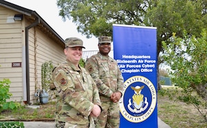 Two Airmen posing with a banner.