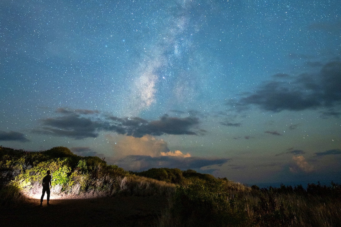 A service member looks up at a starry sky.