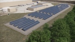 Man in hard hat looking over a solar panel photo voltaic installation.