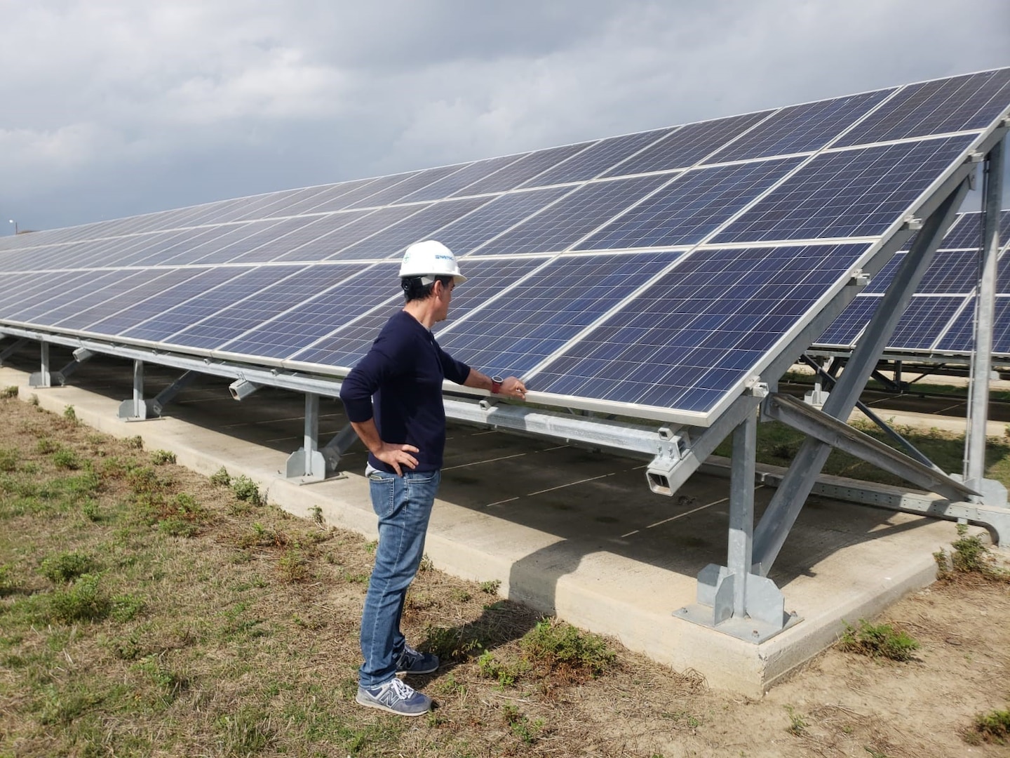 Man in hard hat looking over a solar panel photo voltaic installation.