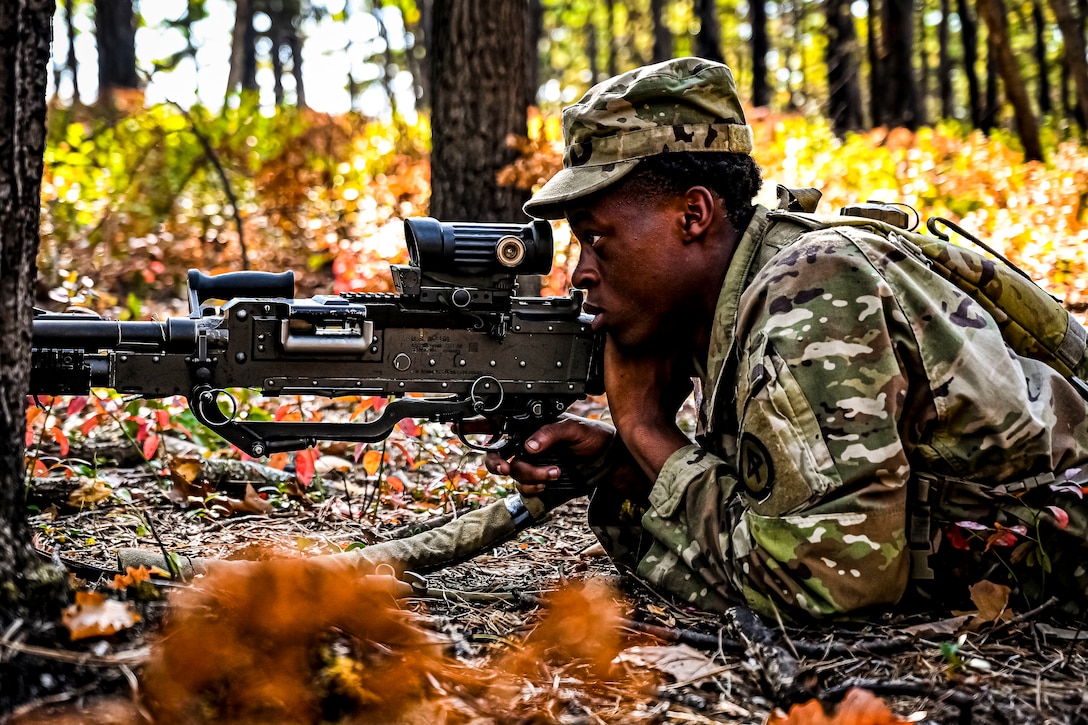 A soldier lying on the ground looks through the sight of his gun.