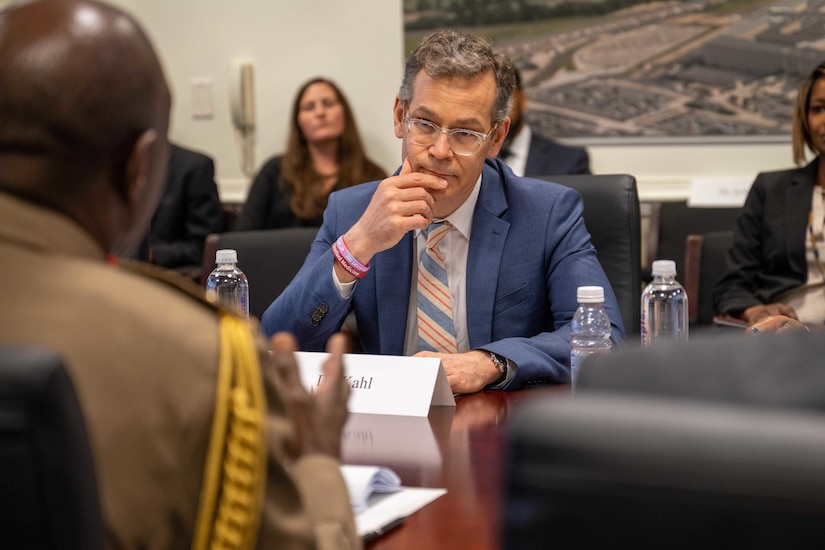 A man at table listens to a conversation.