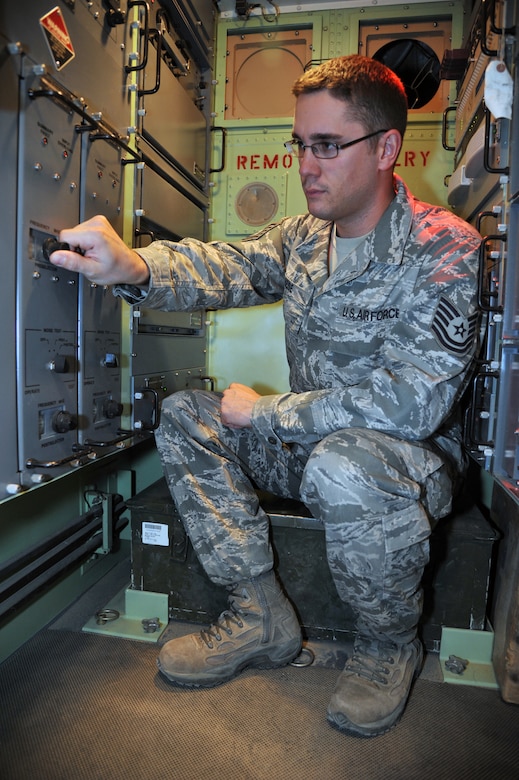 An airman sitting down examines equipment.