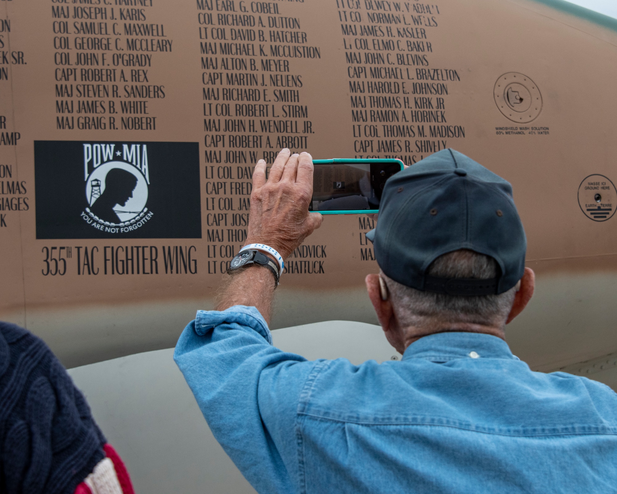 photo of a veteran taking a photo of an aircraft painted in camouflage