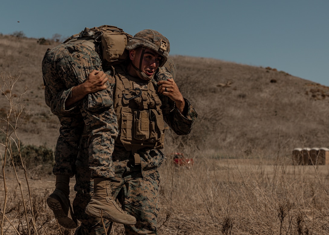 U.S. Marine Corps transmission system operator, with 1st Transportation Battalion, Combat Logistics Regiment 1, 1st Marine Logistics Group, fireman-carries a notional casualty for experimentation of Autonomous Casualty Evacuation (ACE) during Battalion Field exercise 1-23 on Camp Pendleton, California, Oct. 19, 2022. Battalion FX 1-23 is a 1st Transportation Battalion exercise integrated with Project Convergence 22, where Marines and Sailors leverage a series of joint, multi-domain engagements, integrating artificial intelligence, robotics, and autonomy to enhance warfighting capabilities and accelerate decision-making timelines. (U.S. Marine Corps photo by Cpl. Lamas)