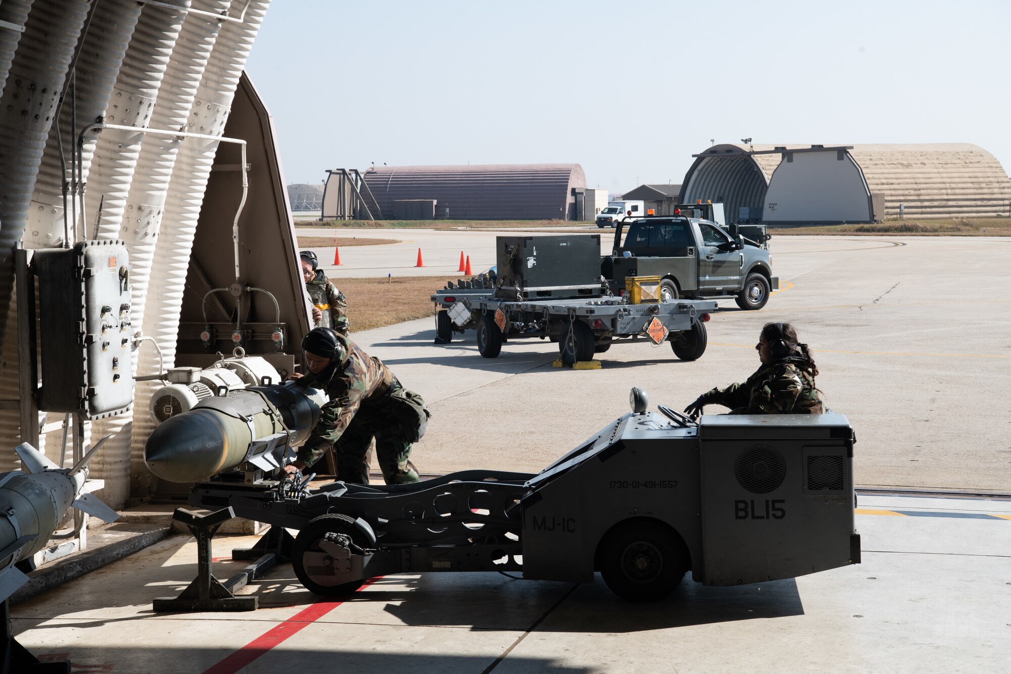 U.S. Air Force Senior Airman Vincent Brown (left) and Airman 1st Class Michelle Santos, both 80th Fighter Generation Squadron weapons load crewmembers, set down a guided-bomb unit-31 using an MJ-1 “jammer” vehicle at Kunsan Air Base, Republic of Korea, Nov. 2, 2022.