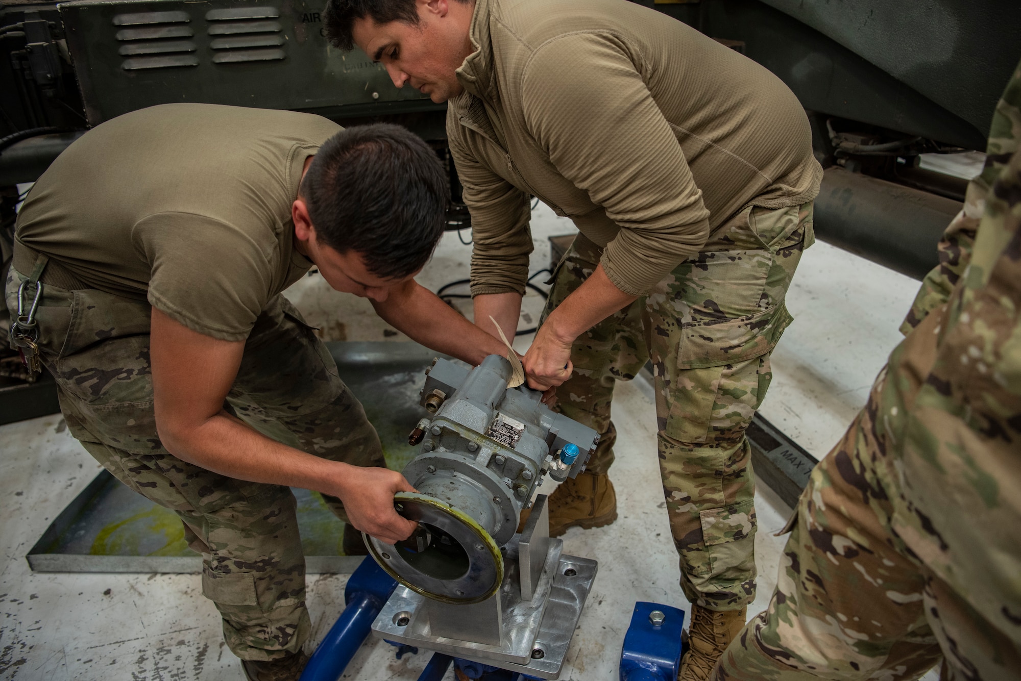 Senior Airman David Resendez, 7th Equipment Maintenance Squadron Air Ground Equipment mechanic, and Staff Sgt. Jacob Pieters, 7th EMS AGE floor lead, lift a hydro pump onto the Face Saver 2000 at Dyess Air Force Base, Texas, Oct. 27, 2022. The Face Saver is a seven-piece item that enables a safer working environment by preventing injuries. (U.S. Air Force photo by Airman 1st Class Ryan Hayman)