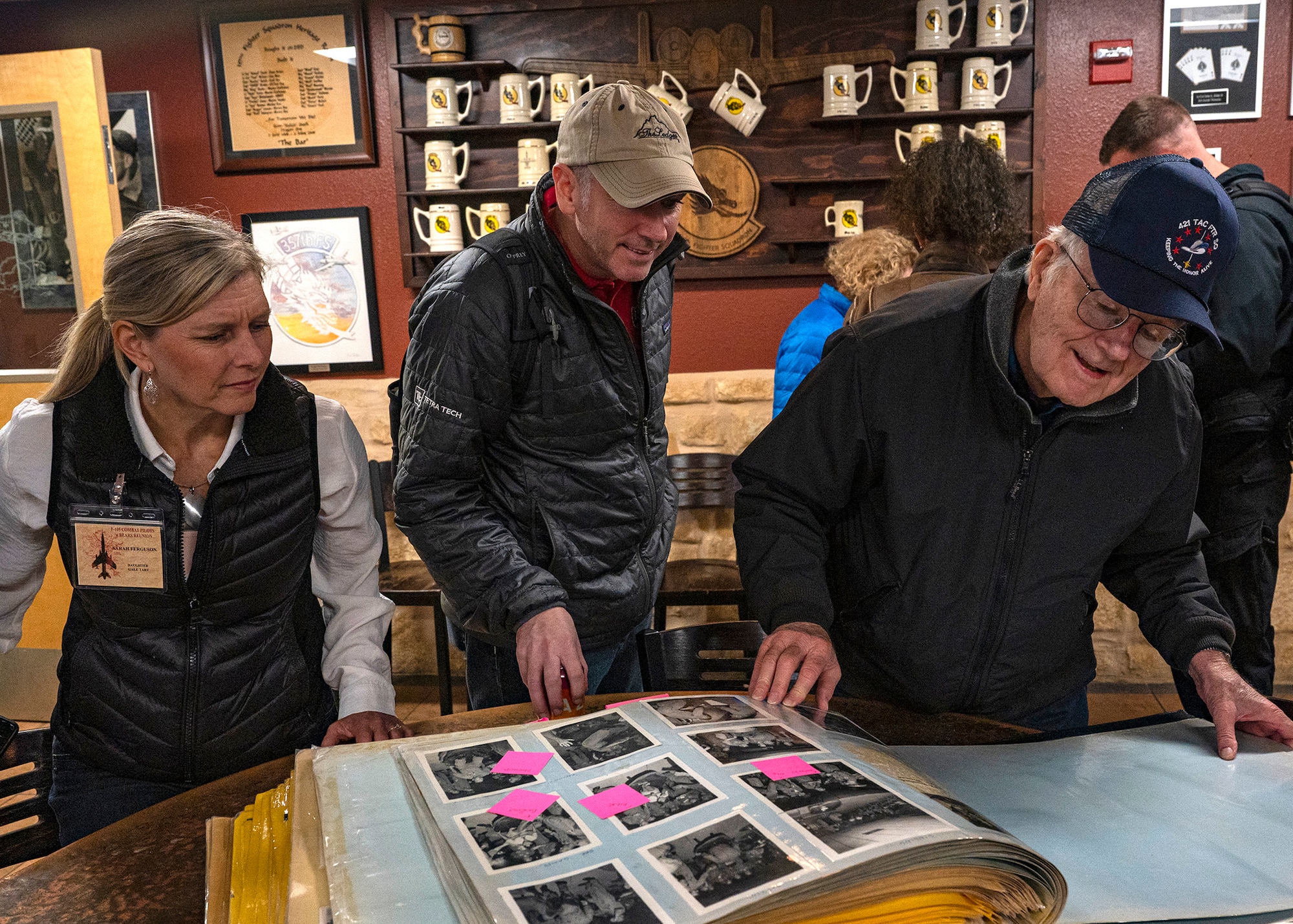 photo of a veteran and his family members looking at an Air Force fighter squadron photo album