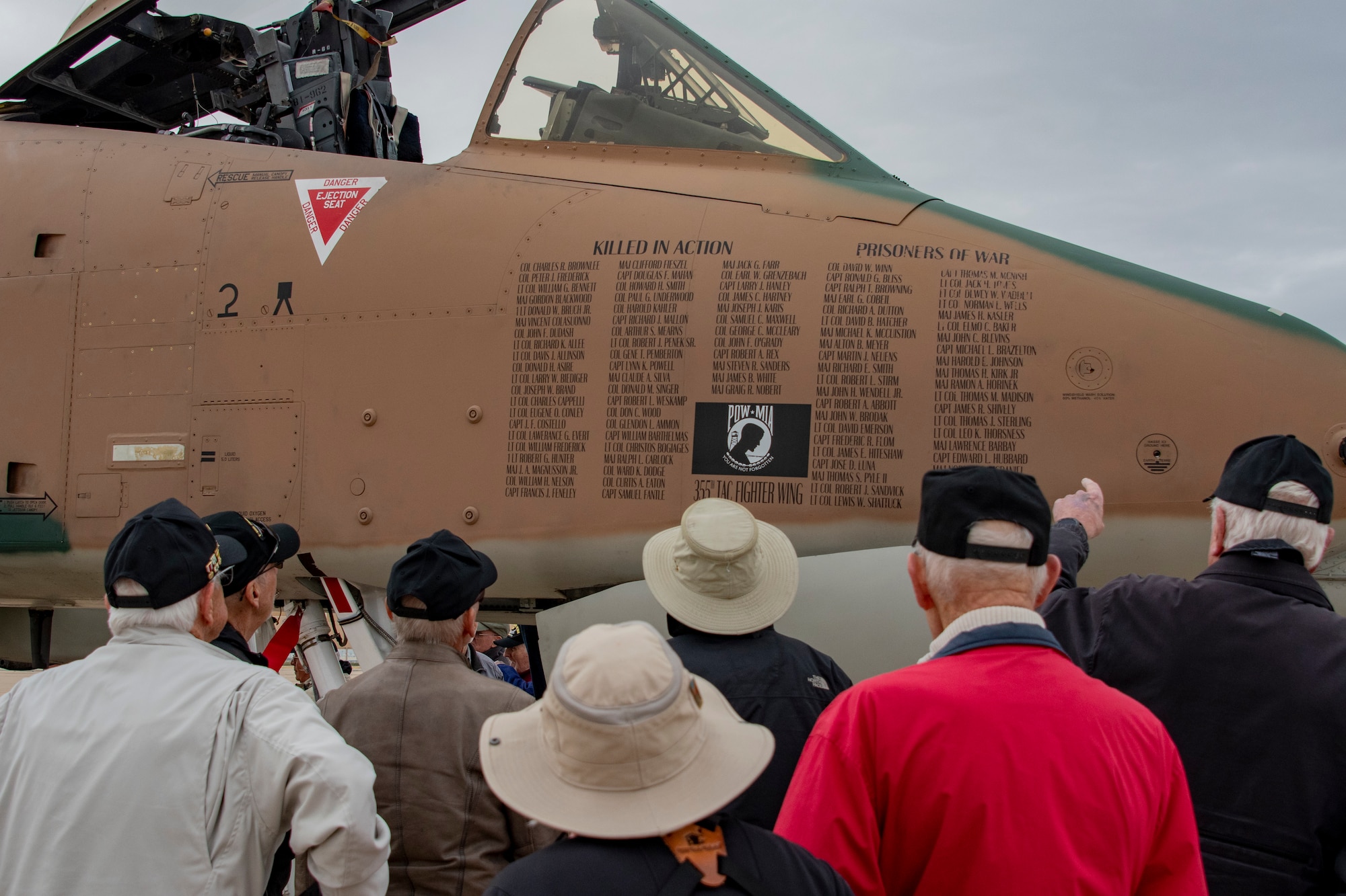 photo of a veterans looking at an aircraft painted in camouflage