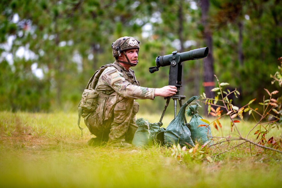 A paratrooper sets up a firing position in a wooded area.