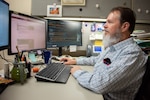 Brent Tolliver, information technology specialist, writes code for the internal intranet page at Brooke Army Medical Center