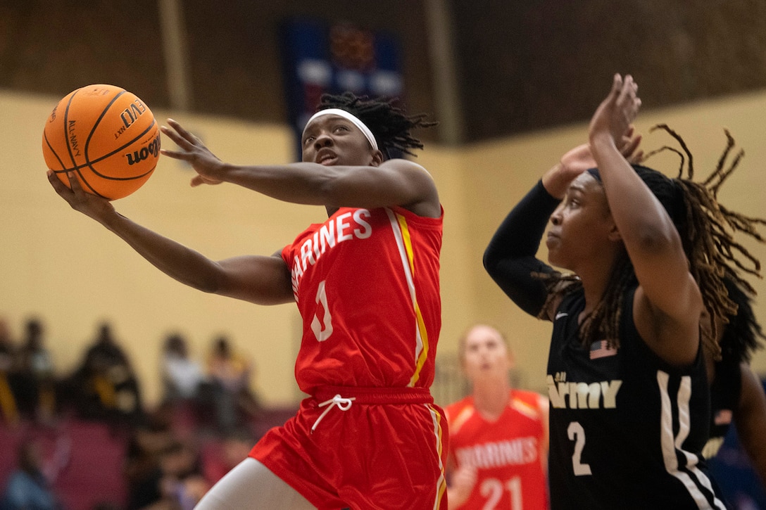 A basketball player tries to block another player from making a shot.