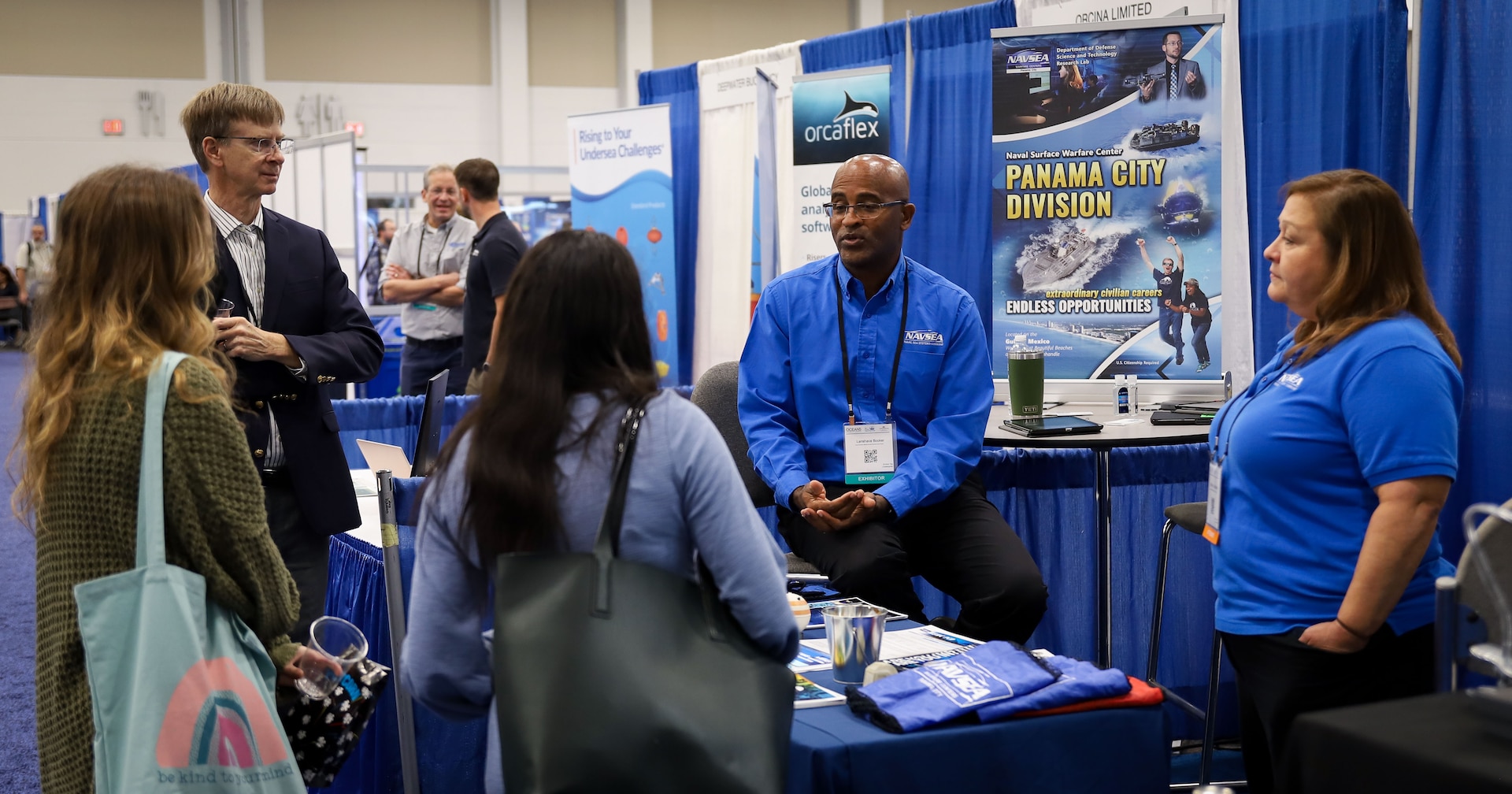 (right to left) Pam Fuhrman, Naval Surface Warfare Center Panama City Division Recruiting and Student Programs lead human resources advisor, and Lanshava Booker, NSWC PCD New Professional technical advisor, speak with several attendees in the exhibition hall at OCEANS 2022 Hampton Roads, Va., Oct. 18. The exhibit hall hosted a student poster competition and a featured a global network of more than 100 exhibition booths within the science, technology and innovation community. (U.S. Navy photo by Jeremy Roman)