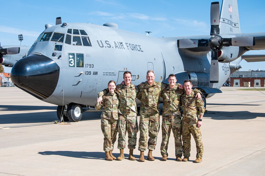 Five airmen pose in front of an aircraft.