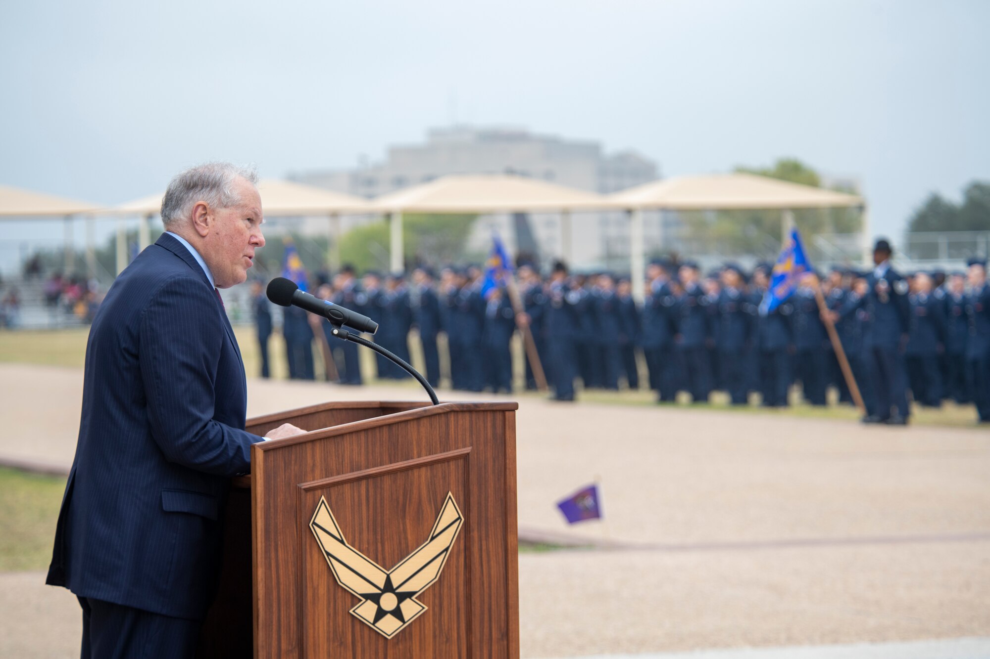 Secretary of the Air Force Frank Kendall reads at a podium to a crowd of Airmen.