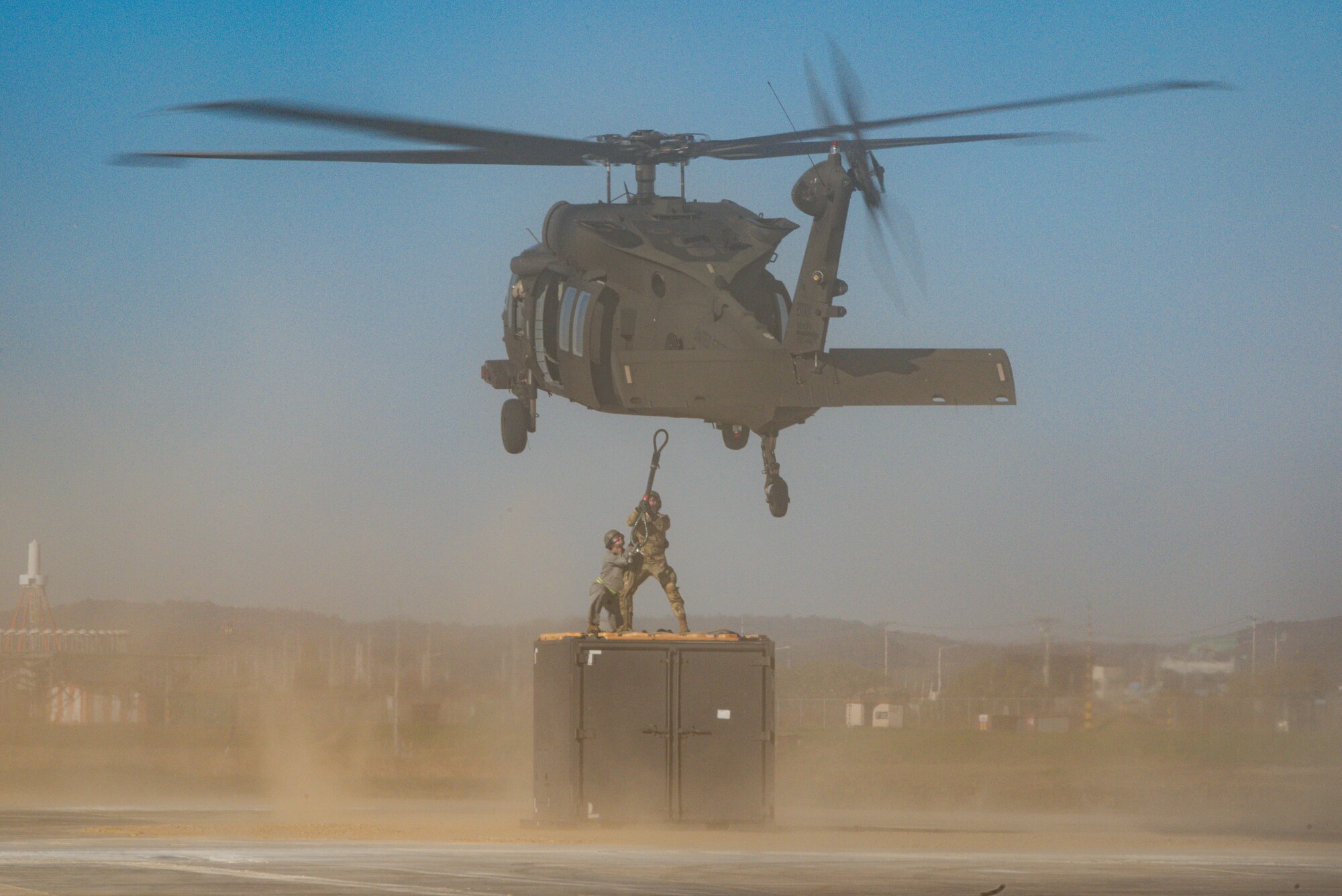 U.S. Air Force Staff Sgts. William Waymouth, 51st Munitions Squadron munitions management crew chief, and Miles Euro, munitions operations supervisor, hook cargo up to a U.S. Army Black Hawk helicopter during a sling load demonstration at Osan Air Base, Republic of Korea, Nov. 4, 2022.