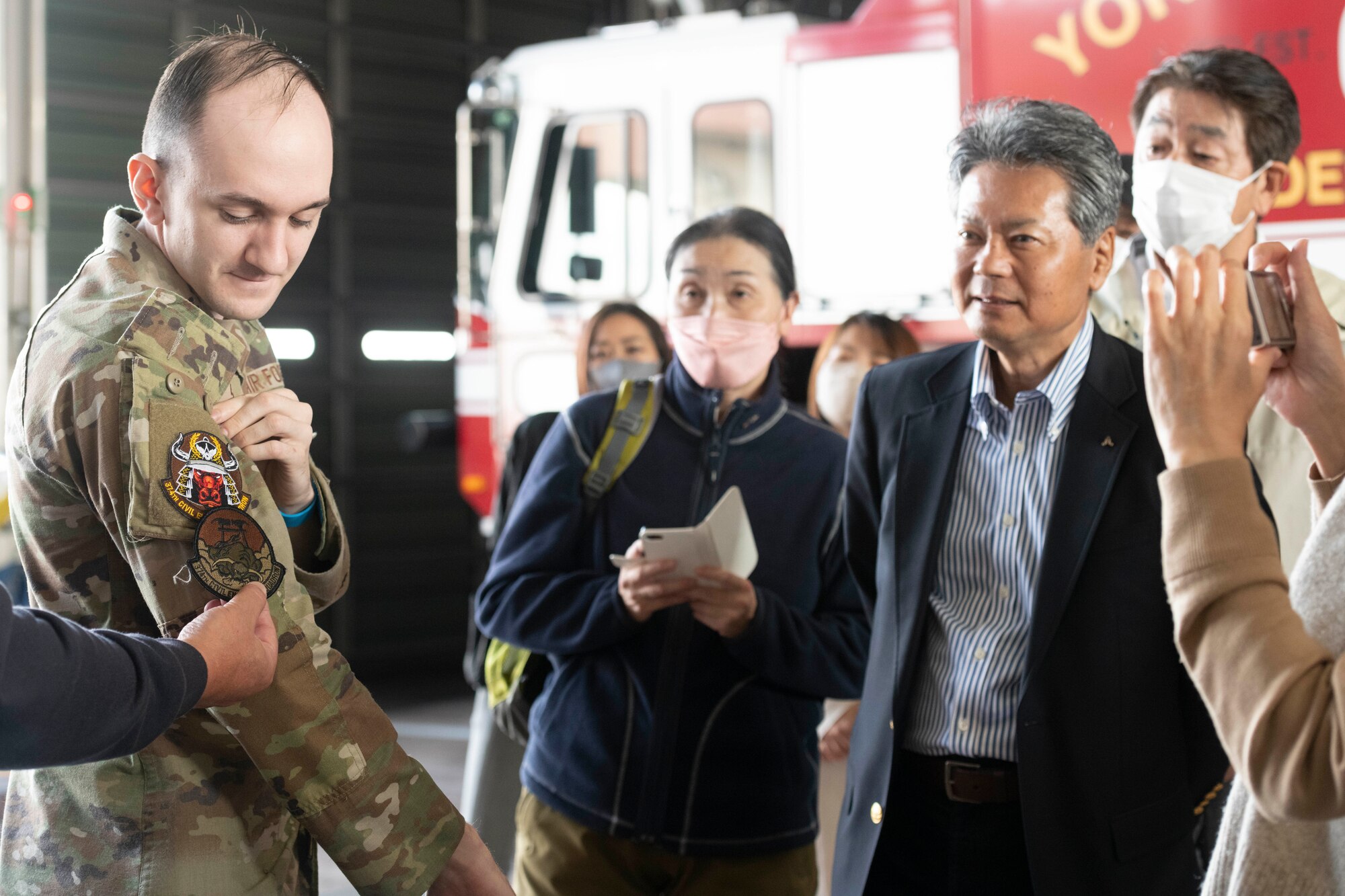 An Airman with the 374th Civil Engineer Squadron shows a morale patch and a squadron patch to members of the Akishima-Yokota Friendship Club during a base immersion tour hosted by the 374th Mission Support Group at Yokota Air Base, Japan, Nov. 4, 2022.