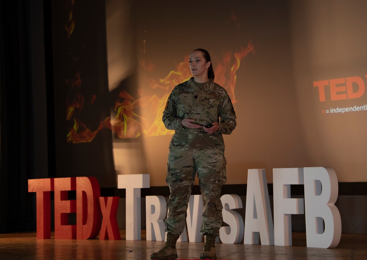 An Airman speaks on a stage.