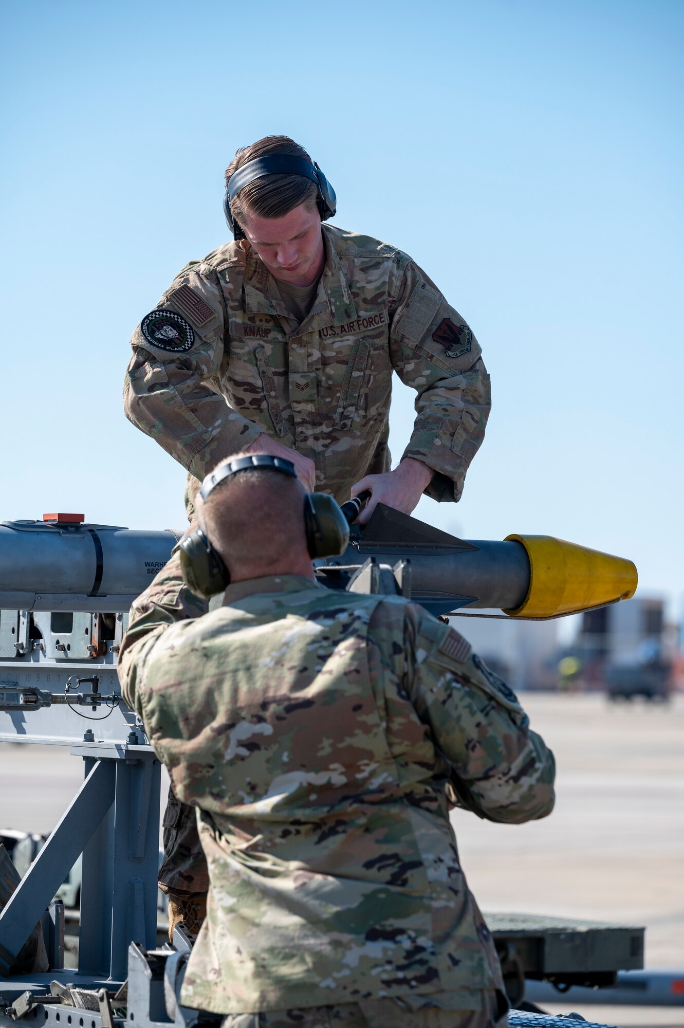 Airmen secure a missile to a cart