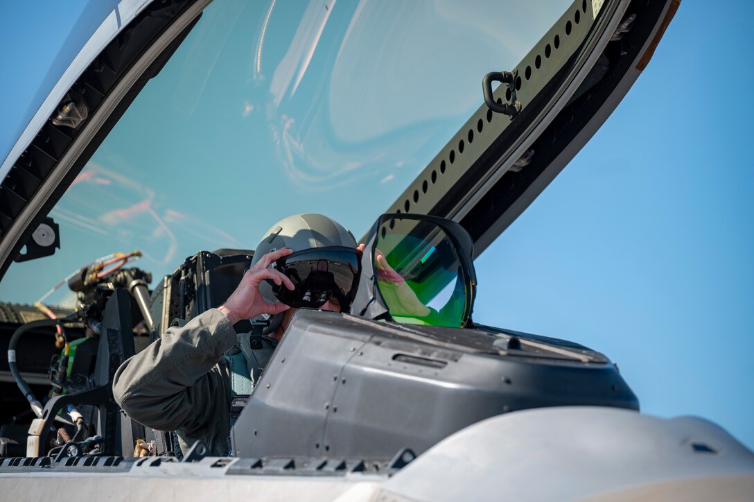 Pilot puts a flight helmet on