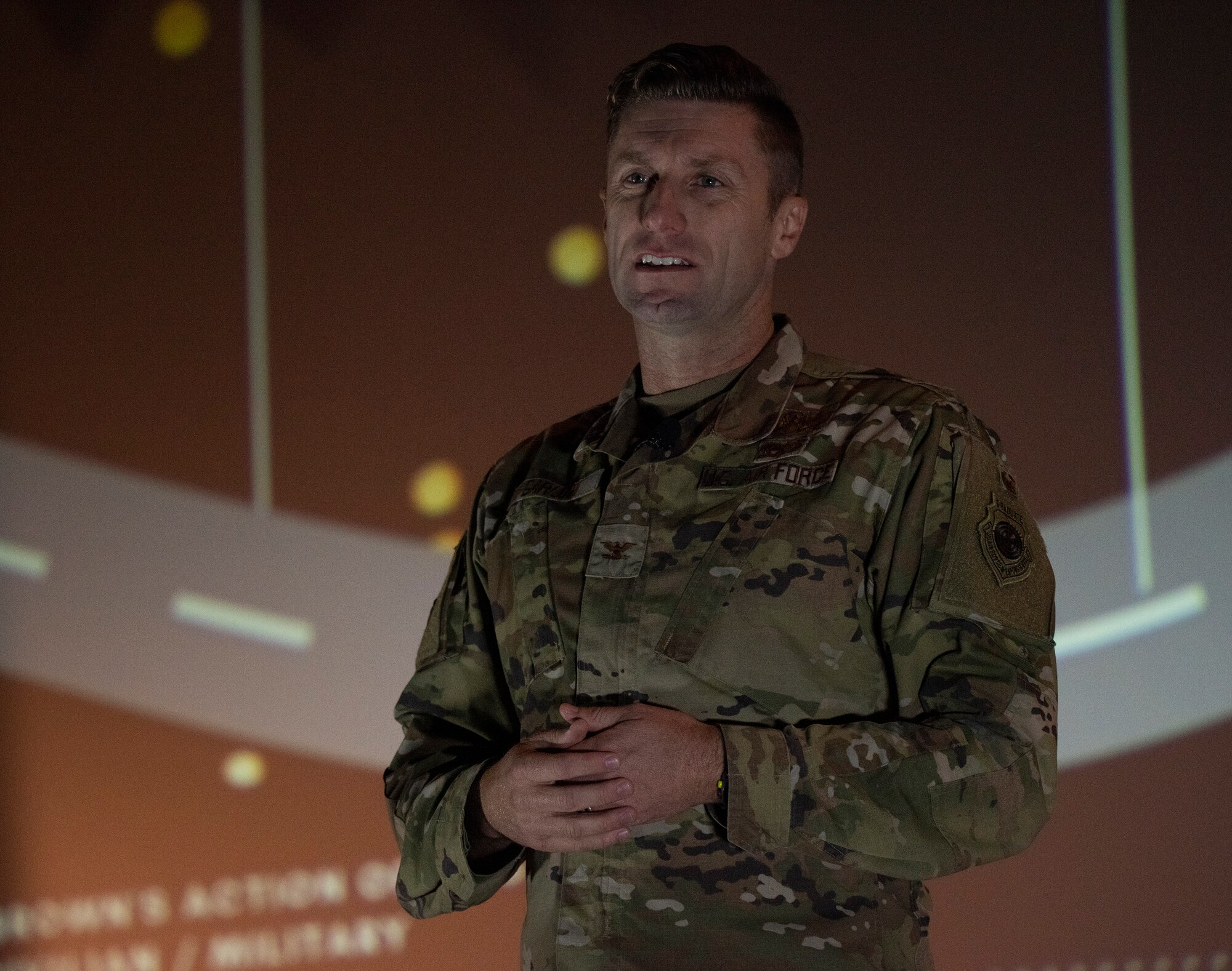 An Airman speaks on a stage.